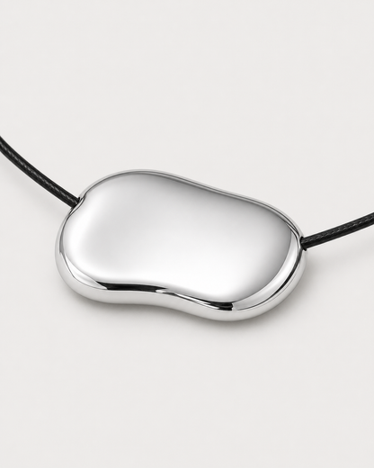 Macro detail of the Orra mirror-polished organic silver bean pendant and black cord