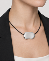 Extreme on-body macro of the Orra organic silver pendant and concealed black cord connections