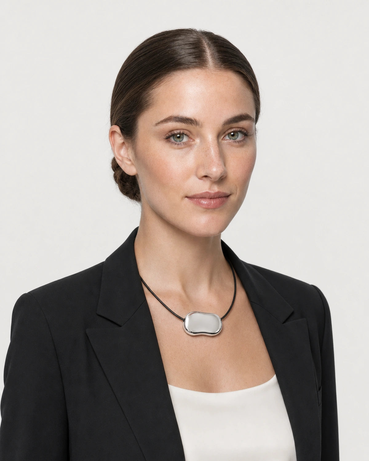 American model aged 27 wearing the Orra silver bean cord necklace in a pale dove-grey studio
