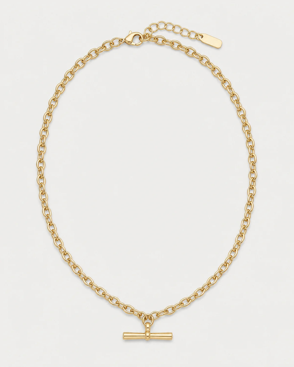 Romy gold sculpted T-bar necklace on a pale dove-grey background