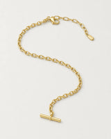 Romy gold-tone T-bar necklace in an alternate curved arrangement on pale grey