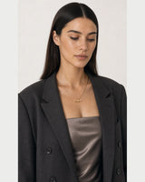 Three-quarter portrait of model looking down at the Romy necklace