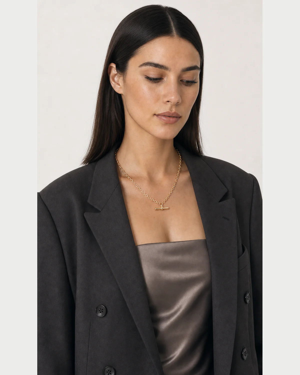 Three-quarter portrait of model looking down at the Romy necklace