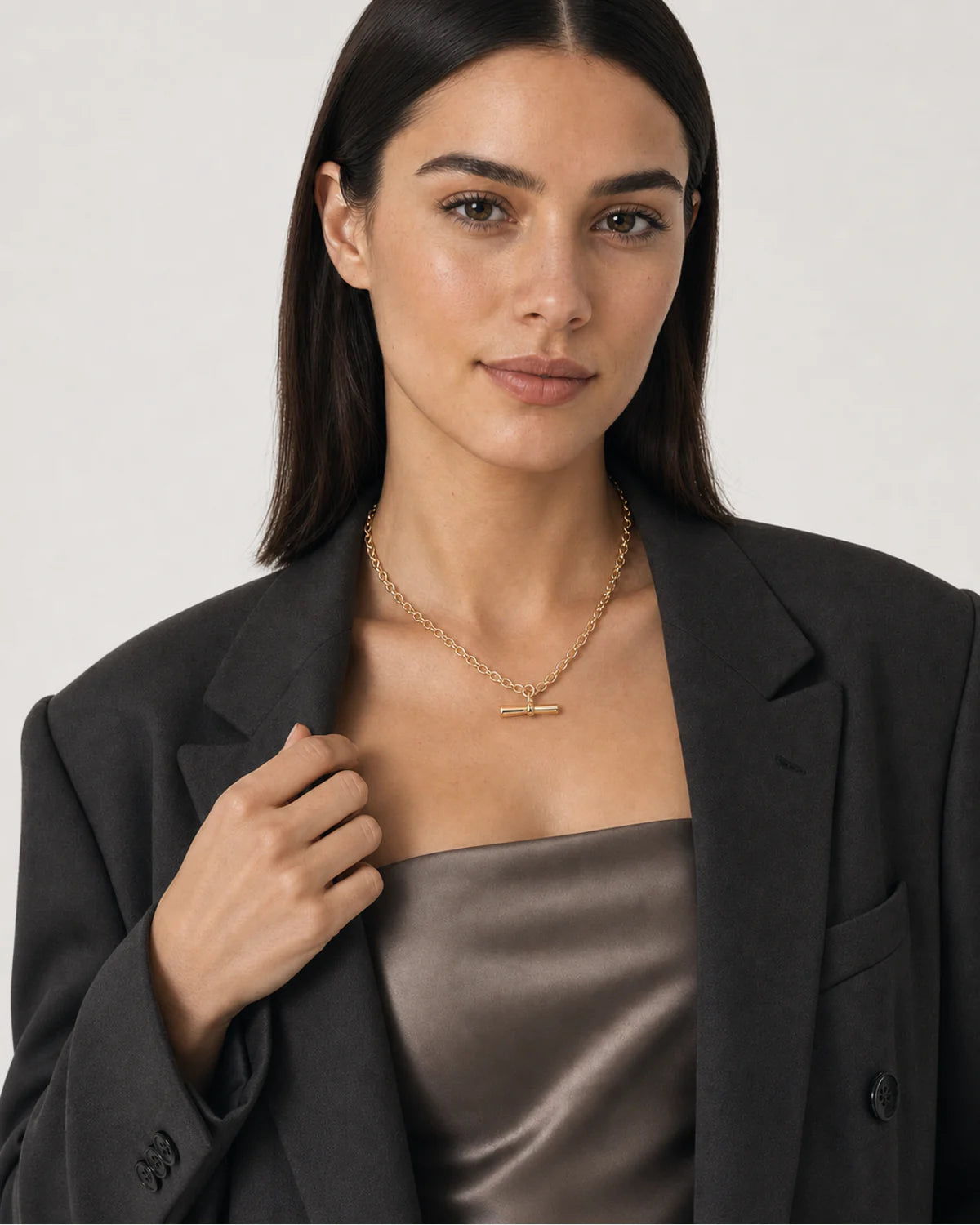 Model holding her blazer lapel while wearing the Romy T-bar necklace