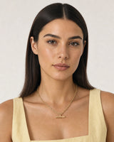 Model in a butter-yellow linen summer top wearing the Romy gold T-bar necklace
