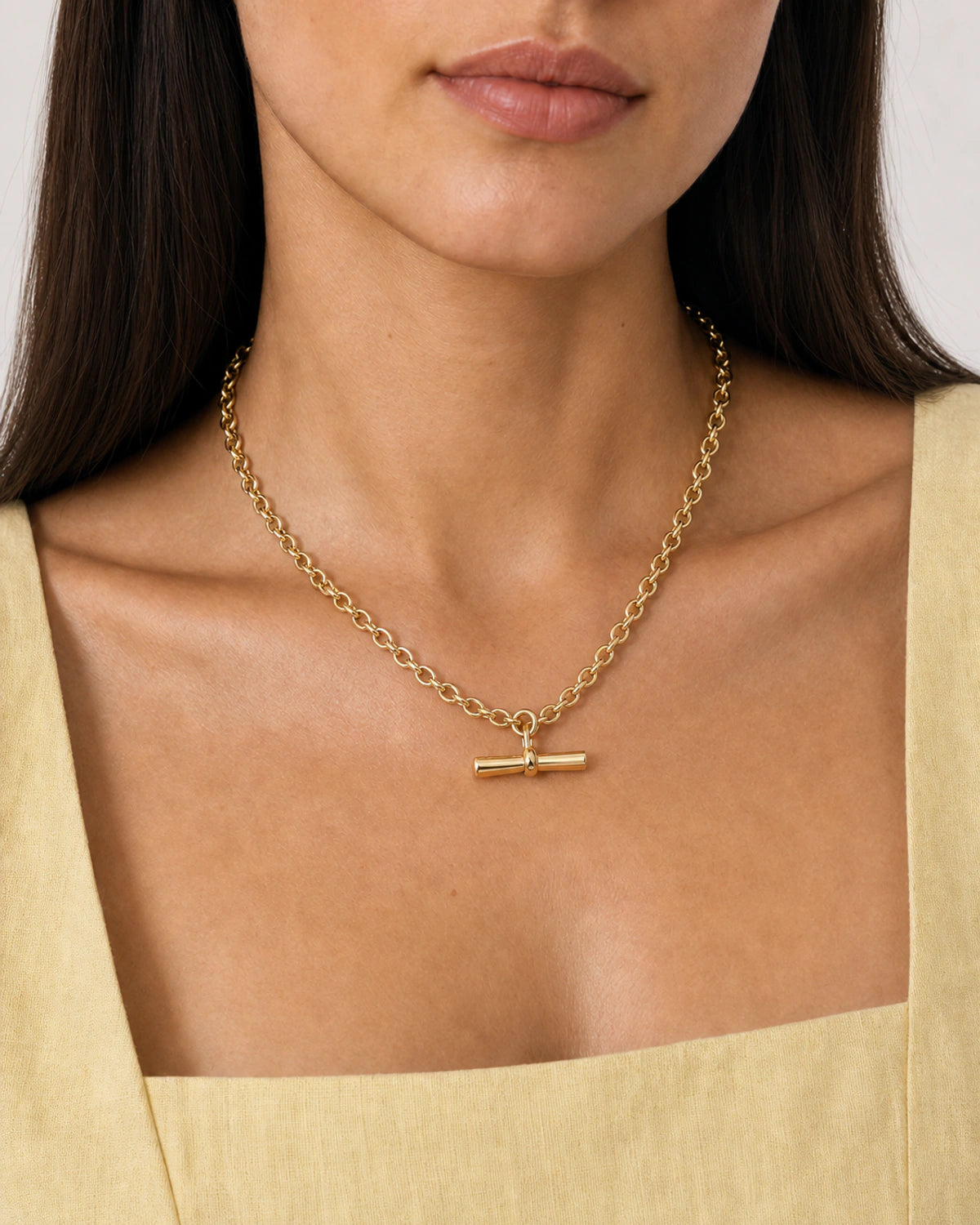 Close wearing view of the Romy gold oval-link chain and sculpted T-bar