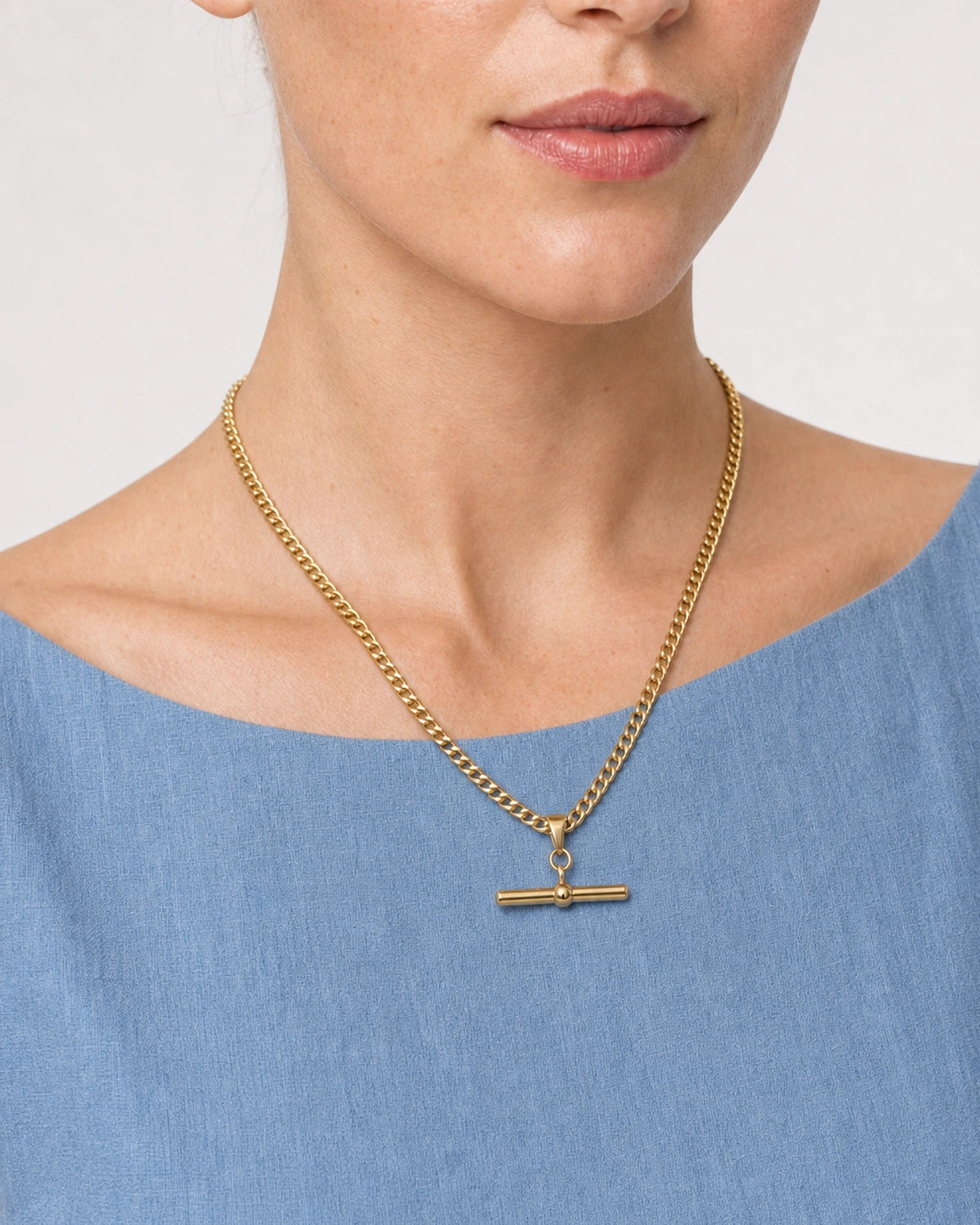 Close wearing view of the Sabine flat curb chain and gold T-bar