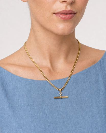 Close wearing view of the Sabine flat curb chain and gold T-bar
