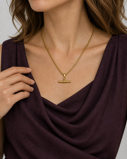 Jewellery-led hand and neckline detail of Evelyn wearing the Sabine T-bar necklace