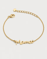 Sera gold script Mama bracelet on a seamless pale dove-grey studio background
