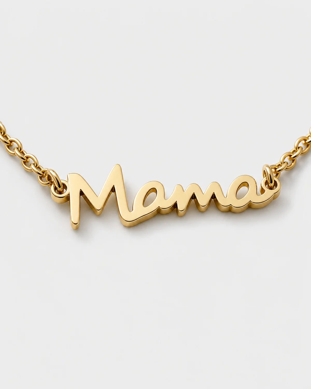 Macro detail of the polished connected Mama script and fine gold chain