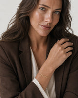 Australian model aged 25 to 28 wearing the Sera Script Mama Bracelet in a pale dove-grey studio