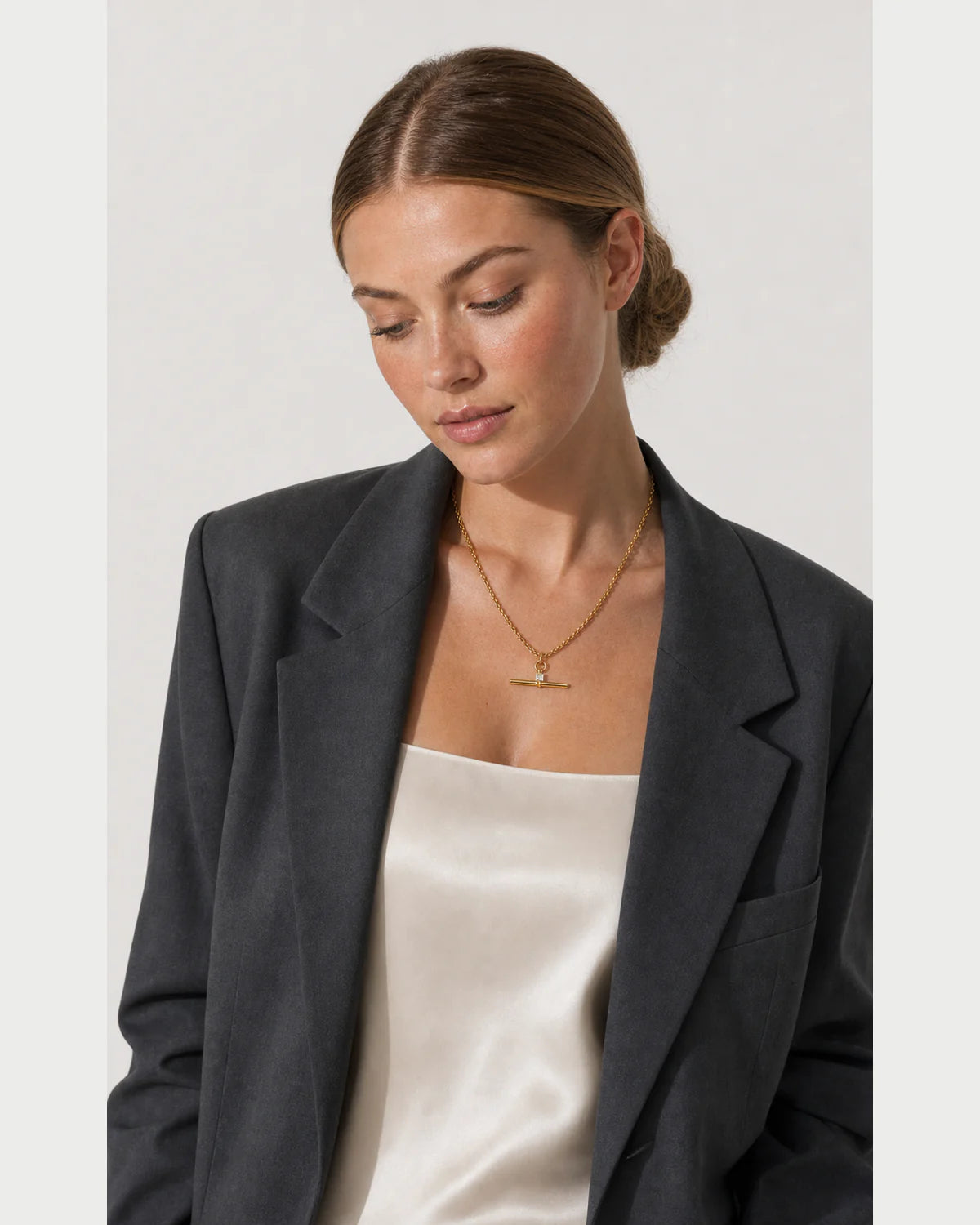 Three-quarter portrait of model looking down at the Sloane crystal necklace