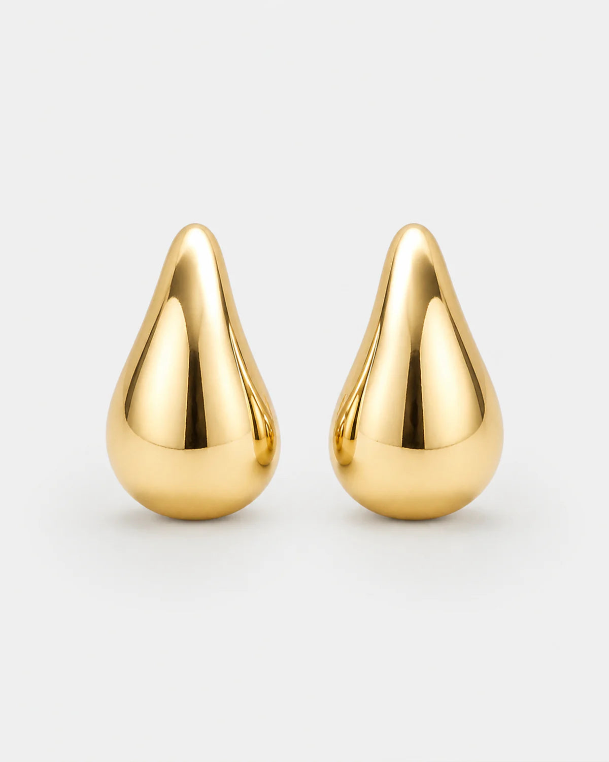Solène gold sculpted teardrop stud earrings on pale dove-grey