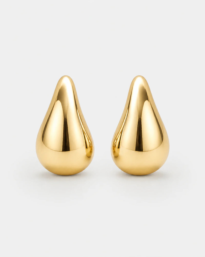 Solène gold sculpted teardrop stud earrings on pale dove-grey