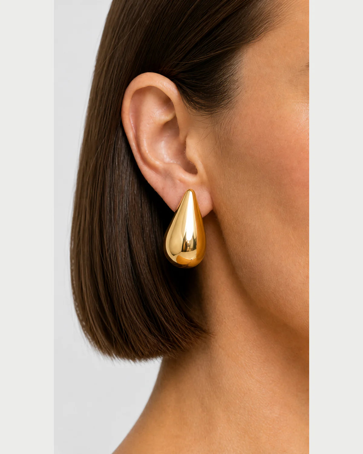 Extreme on-ear macro of the Solène sculpted gold teardrop