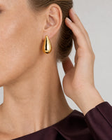 Eye-free hair gesture beside Lydia's gold Solène teardrop earring