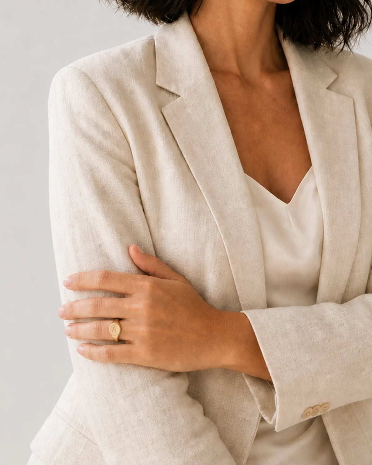 Human-scale view of the Solenne signet ring against ivory tailoring