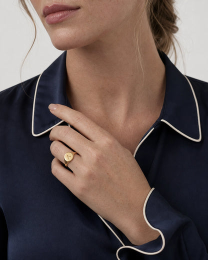 British model tracing her navy collar while wearing the gold Solenne initial ring