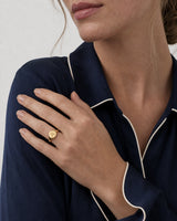 Shoulder pose wearing the gold Solenne oval initial A signet ring