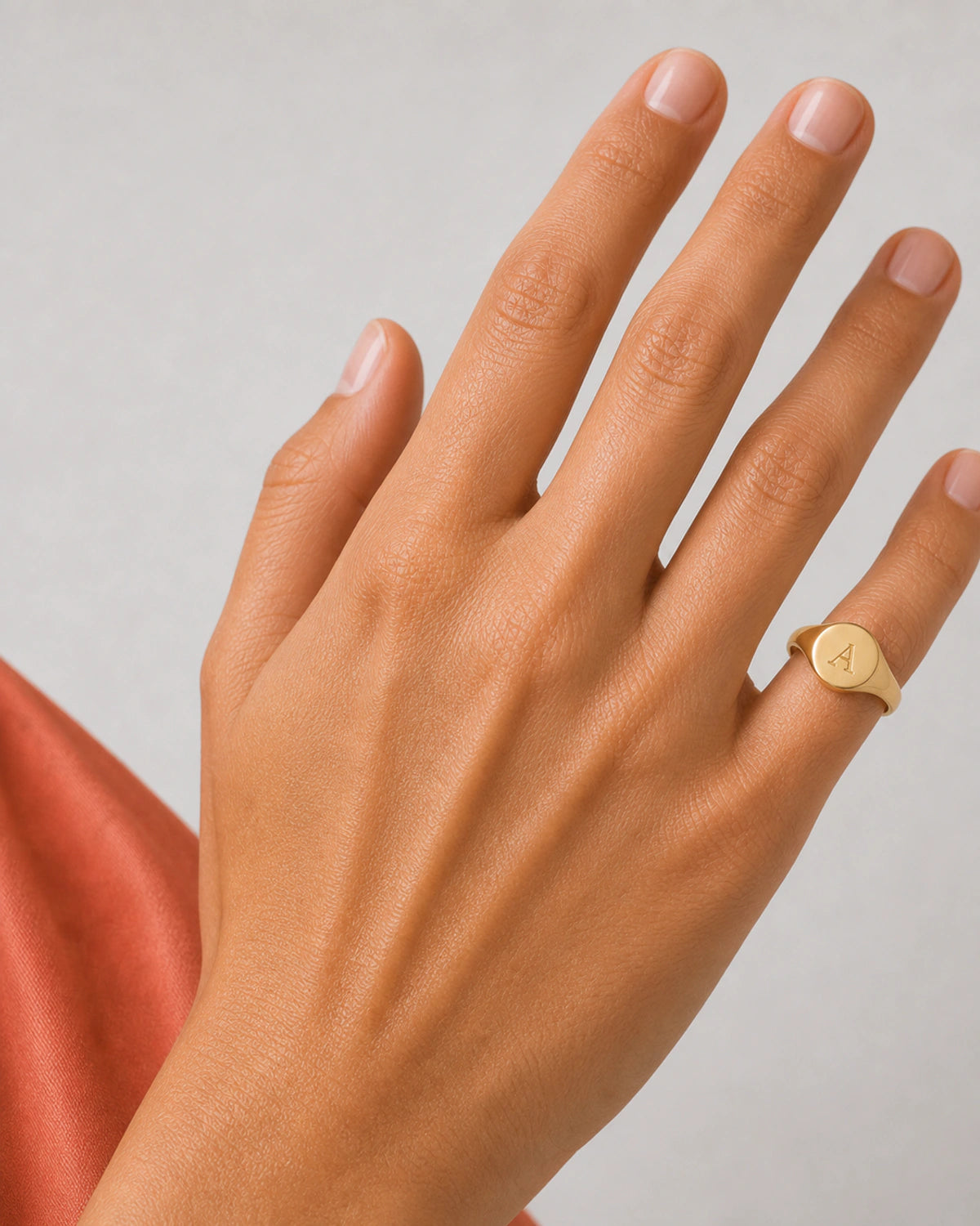Close wearing view of the polished gold Solenne signet engraved with A