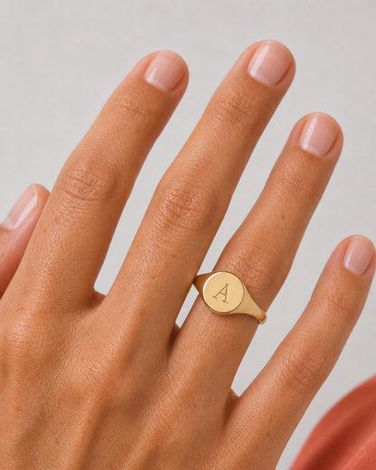Extreme on-hand macro of the Solenne gold oval signet and serif A engraving
