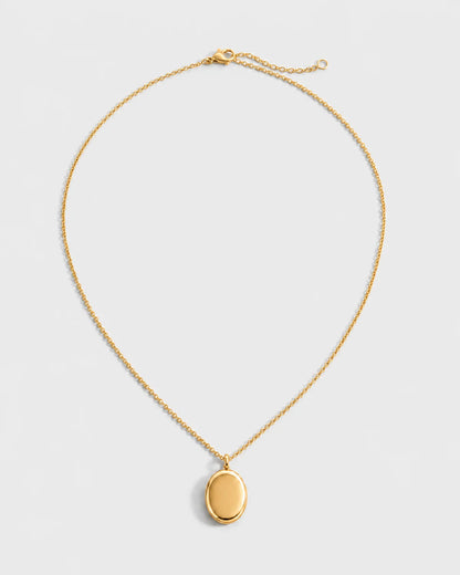 Solenne blank gold oval pendant necklace on a seamless pale dove-grey studio background