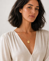 Australian model aged 24 to 28 wearing the Solenne blank oval pendant in a pale dove-grey studio
