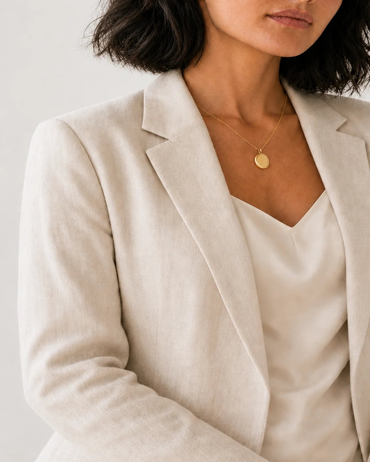 Human-scale view of the Solenne pendant against ivory tailoring