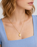 Alternate mouth-and-chin-down portrait wearing the gold Solenne signet pendant