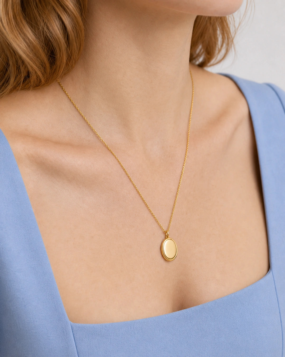 Jewellery-led neckline detail of the gold Solenne pendant on cornflower blue