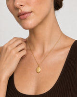 Close wearing view of the blank polished gold Solenne oval pendant