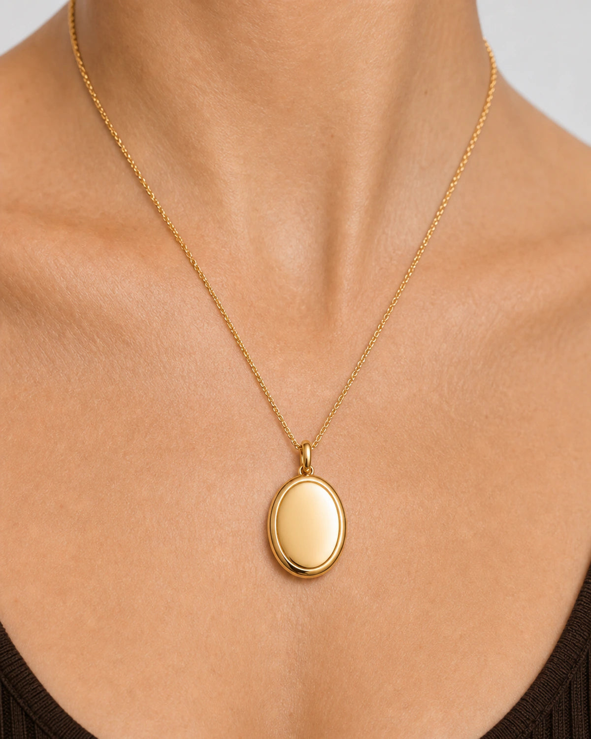 Extreme on-body macro of the Solenne blank oval pendant, bail and fine chain