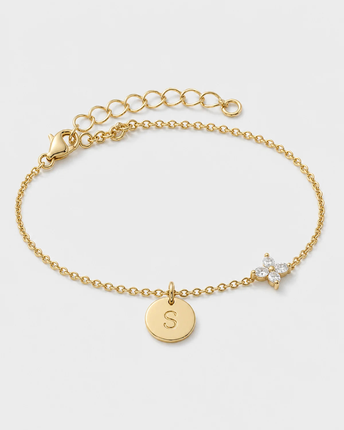 Soline gold initial S and four-stone flower bracelet on pale dove-grey