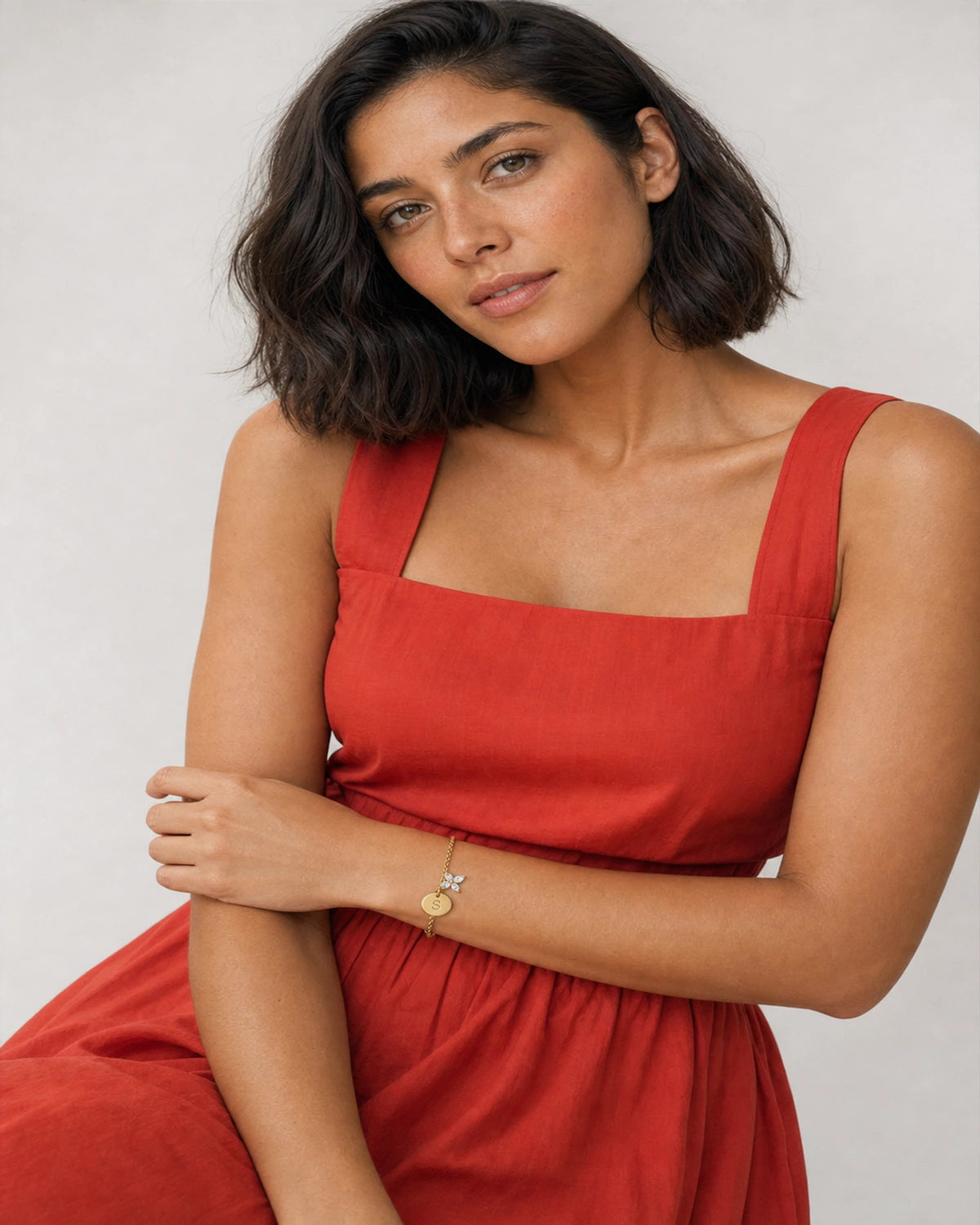 Model in a tomato-red summer sundress wearing the Soline initial S bracelet