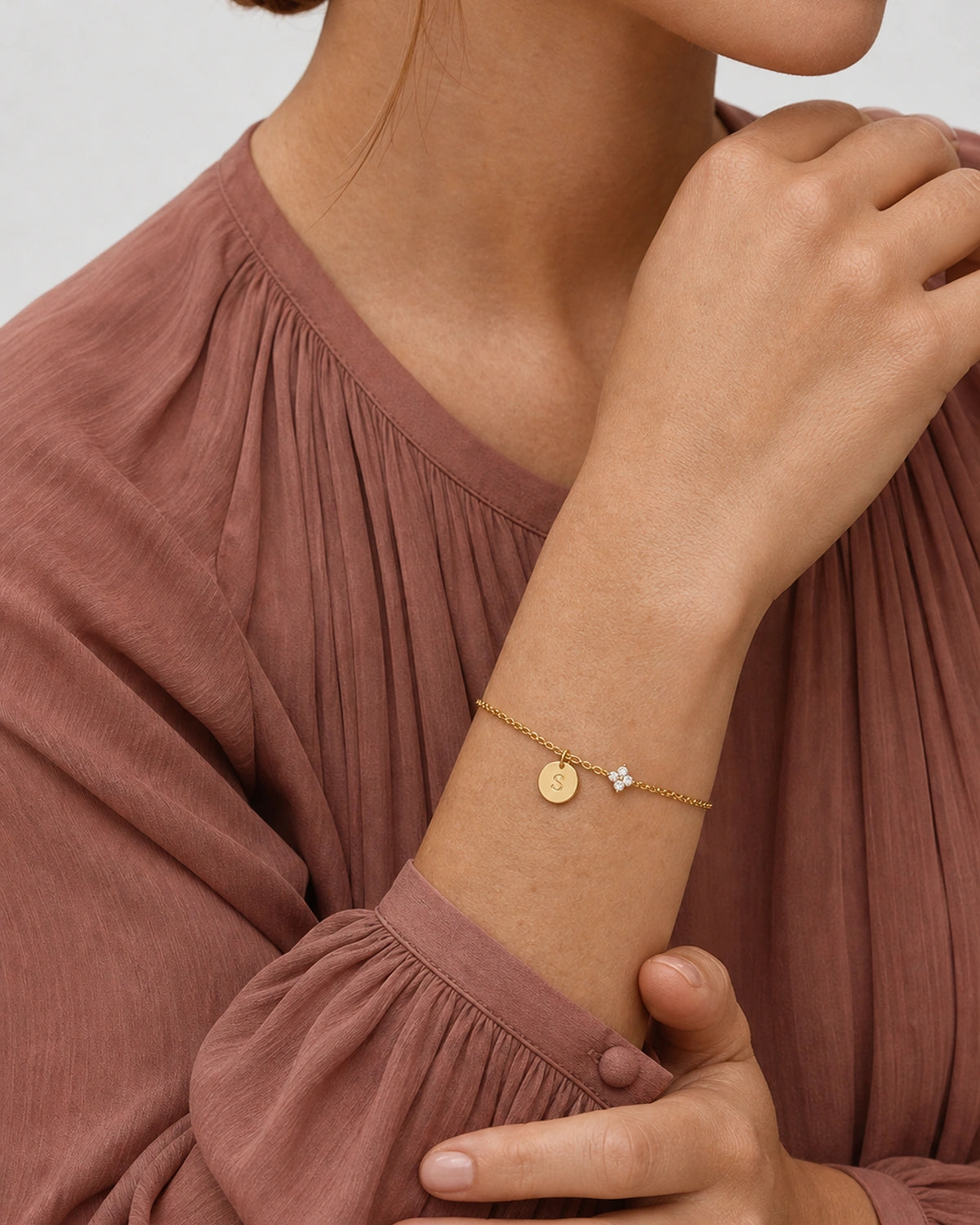Supported forearm pose wearing the gold Soline initial S bracelet