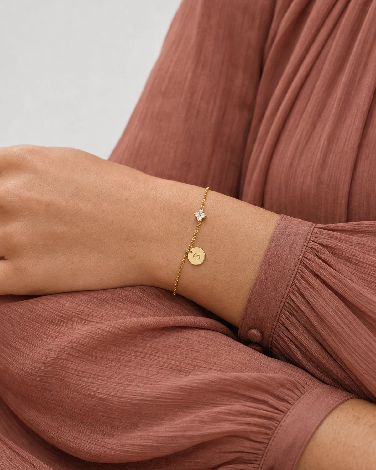 Palm-down sleeve study wearing the gold Soline initial bracelet