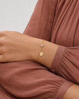 Palm-down sleeve study wearing the gold Soline initial bracelet
