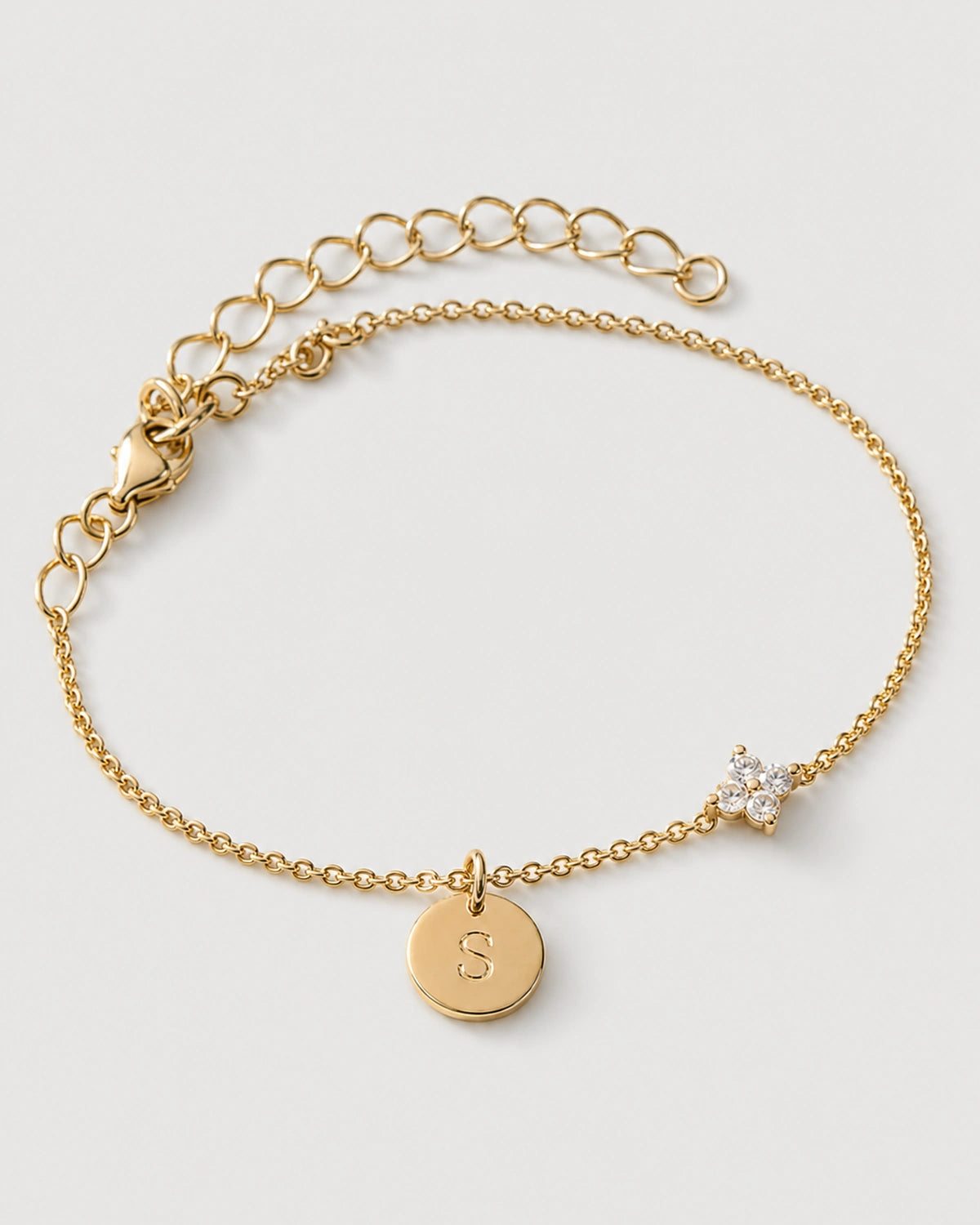 Gold Soline initial S and four-marquise flower bracelet hero on pale neutral grey