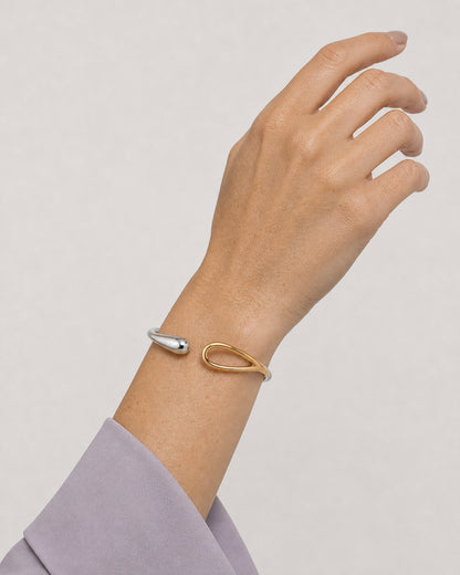 Raised-wrist view of Madeleine wearing the Sora silver and gold open bangle