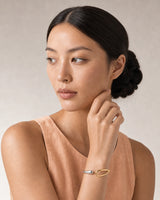 Close wearing view of the Sora silver droplet and gold loop terminals