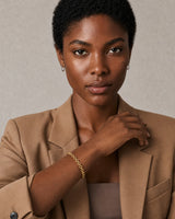 Short-haired model wearing the Talia gold bracelet with a poised direct gaze
