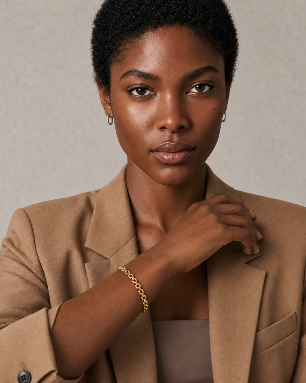 Short-haired model wearing the Talia gold bracelet with a poised direct gaze
