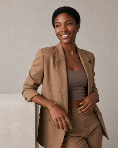 Model in camel tailoring wearing the Talia bracelet with a genuine smile