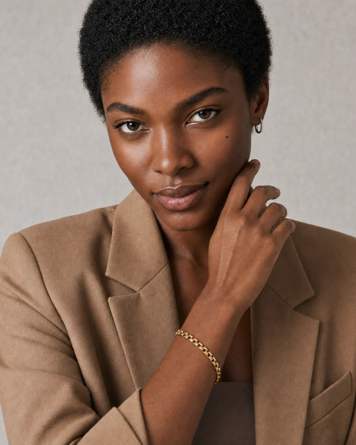 Model lifting her hand near her jaw while wearing the Talia gold bracelet