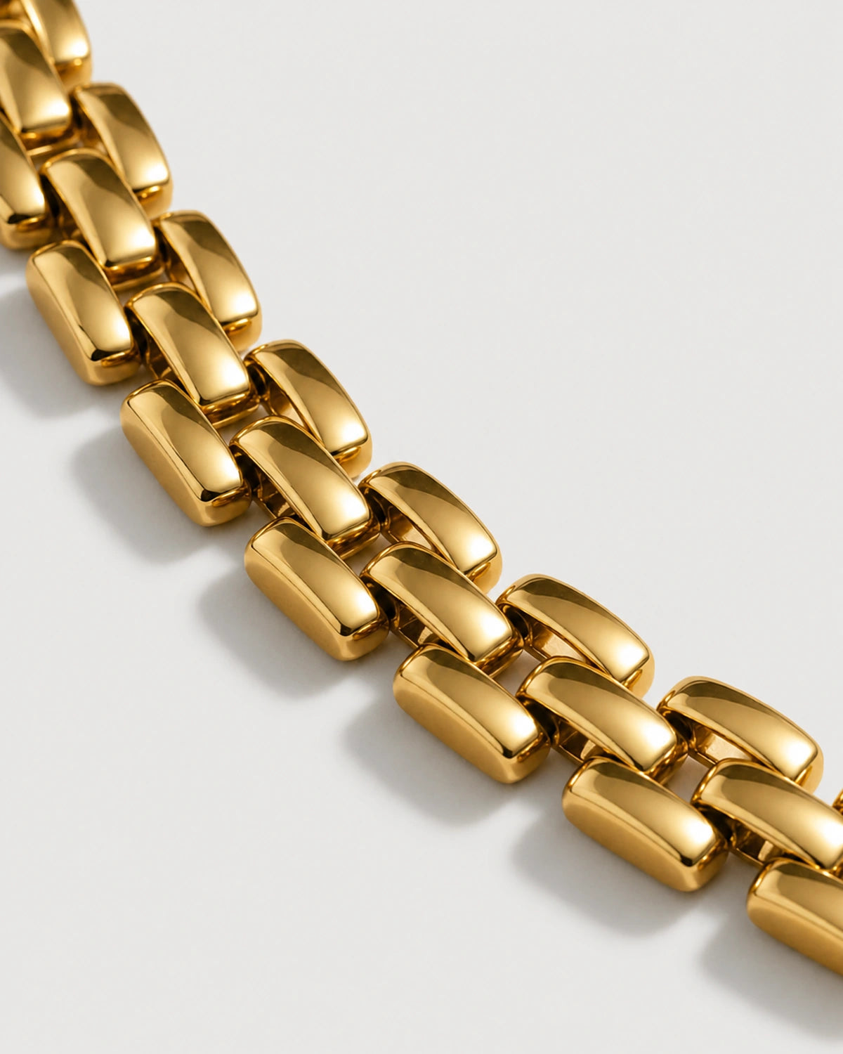 Macro view of Talia polished gold articulated watch links on limestone