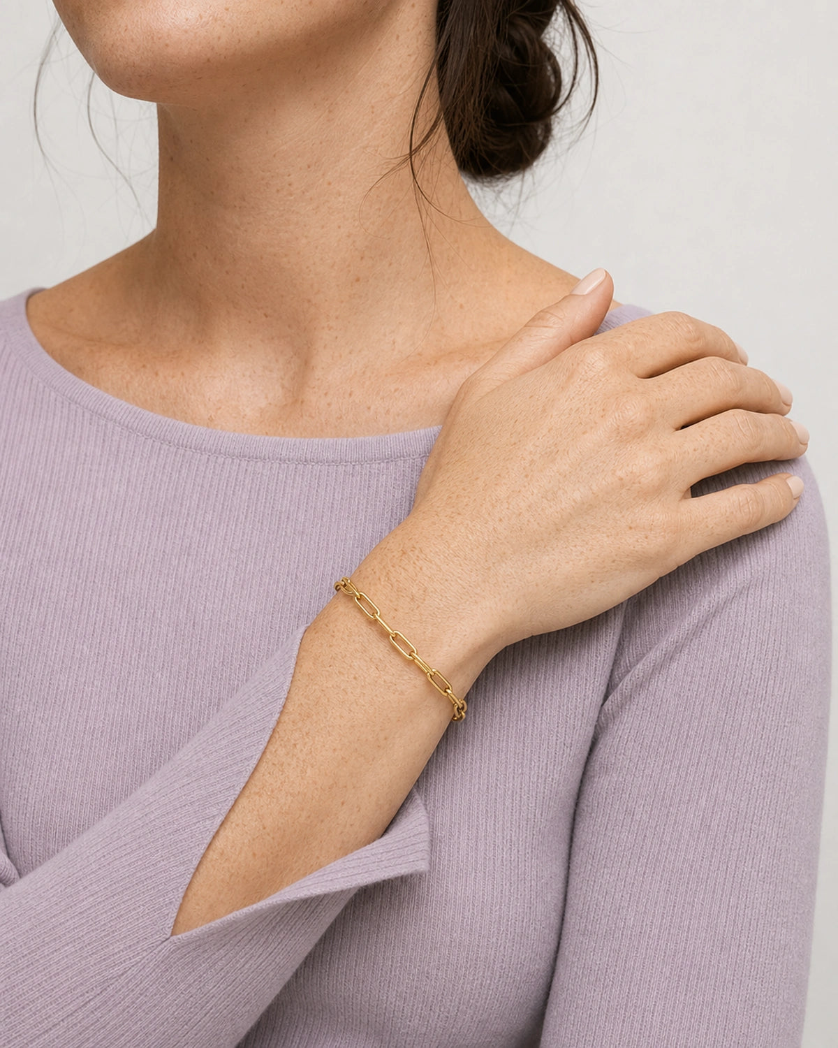 Crossed-wrist wearing view of Vela gold paperclip bracelet