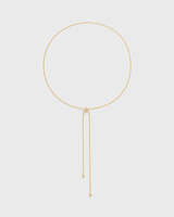 Vela fine gold slider lariat necklace on a seamless pale dove-grey studio background