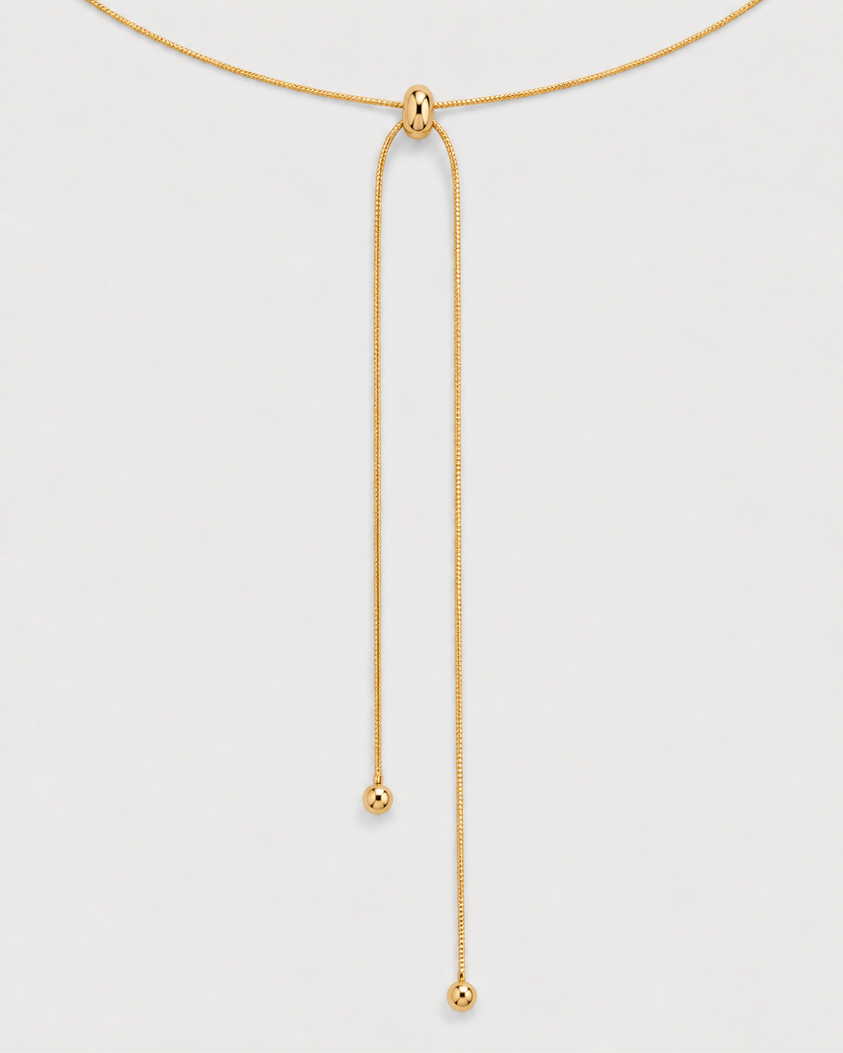Macro detail of the Vela polished slider and two unequal ball-tipped gold tails