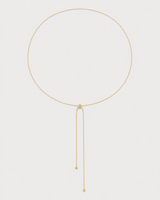 Alternate full-length view of the fine gold Vela slider lariat on pale dove-grey